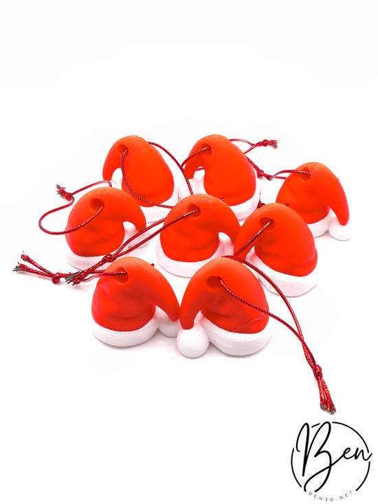 Gorros de Papá Noel rojos con borde y pompón blancos, vistos desde arriba con cordones para colgar