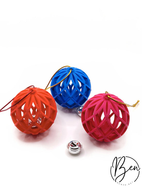 Bolas navideñas caladas en naranja, azul y rosa junto a pequeños cascabeles plateados