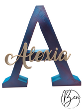 Letra A decorativa en tonos azules con el nombre Alexia en relieve